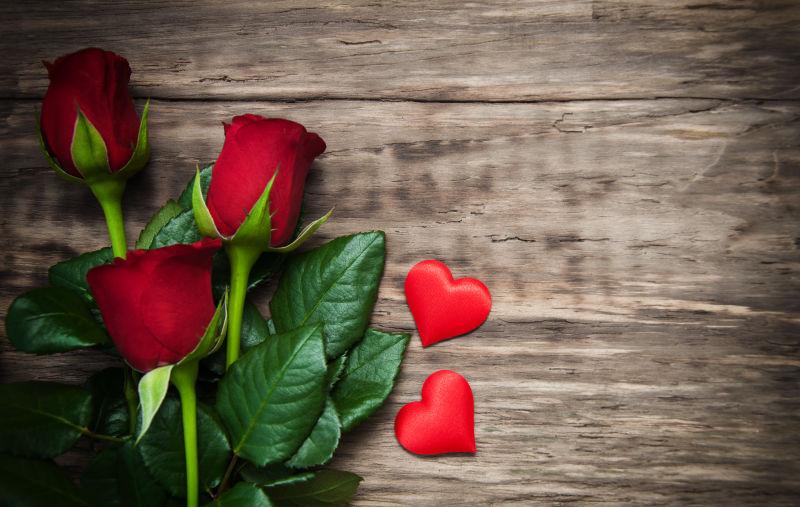 旧木桌上的红心和红玫瑰