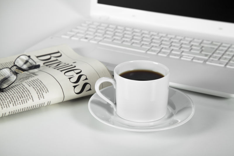 白色桌子上的笔记本电脑和报纸一杯咖啡