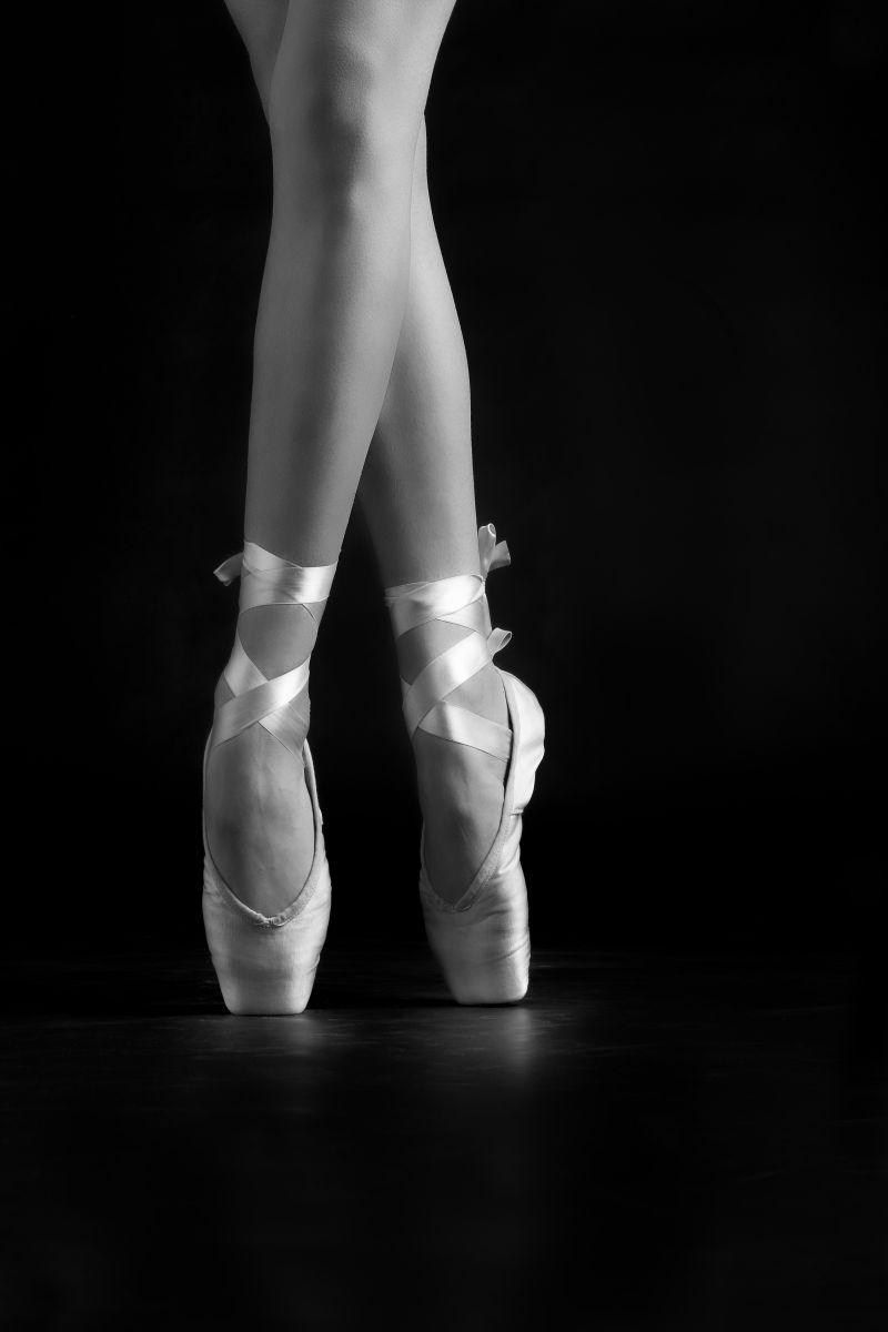 黑色背景下的芭蕾舞演员的腿和鞋