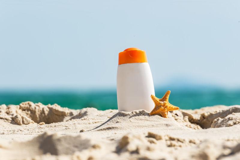 白色瓶装防晒霜和海星在热带海滩