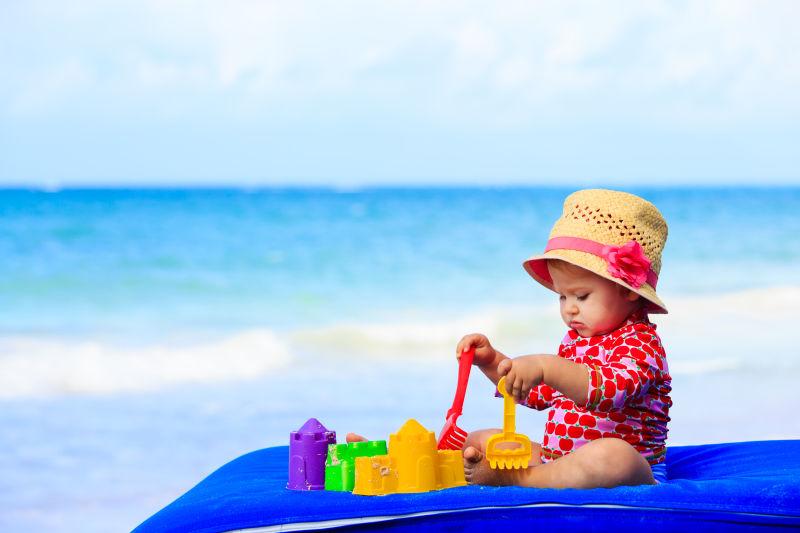 沙滩边玩沙水玩具的小女孩