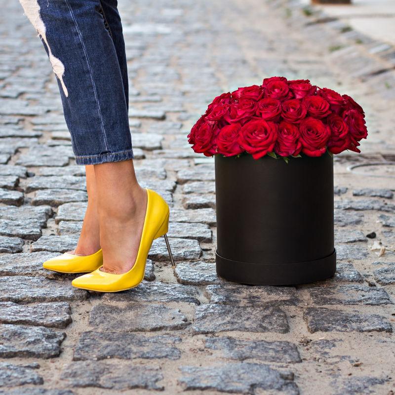 红色玫瑰一旁的穿黄色高跟鞋的美女腿部
