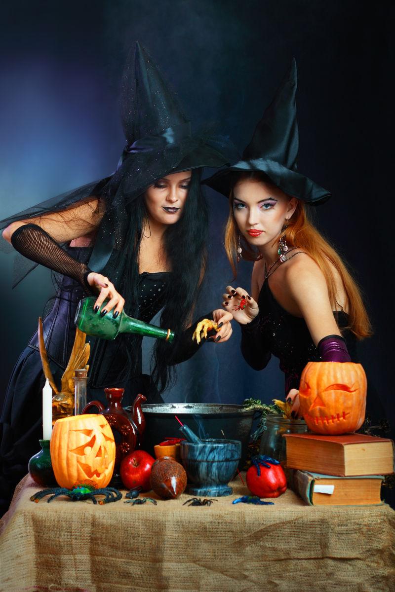 两个迷人的万圣节女巫在黑暗的背景下制造药水