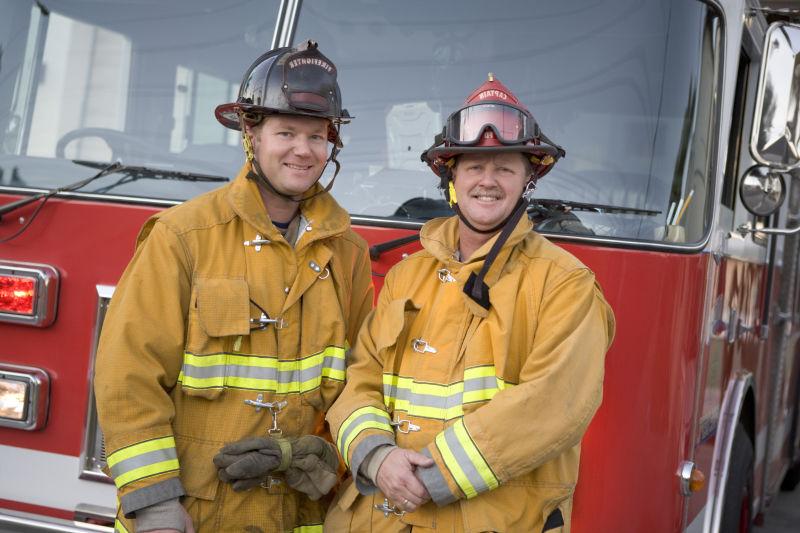 消防车前微笑的两个消防员