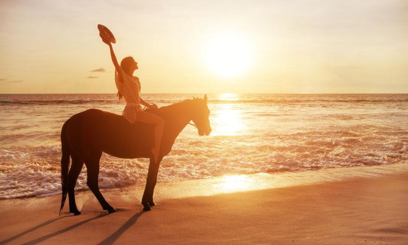 美女在海岸线骑着心爱的马