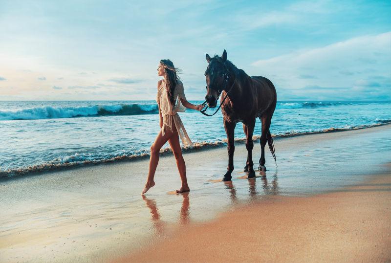 身材苗条的美女带着一匹马在海边散步
