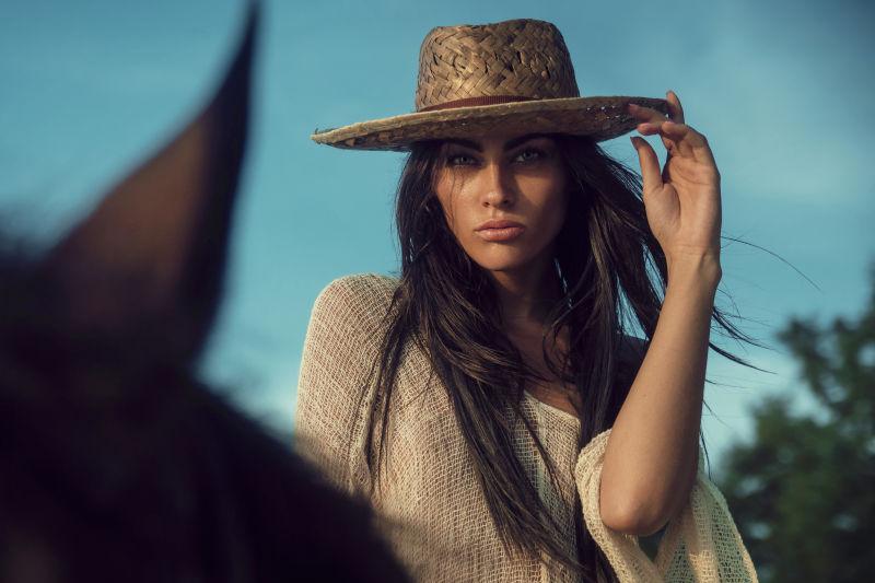 骑在马背上的戴帽子的美女