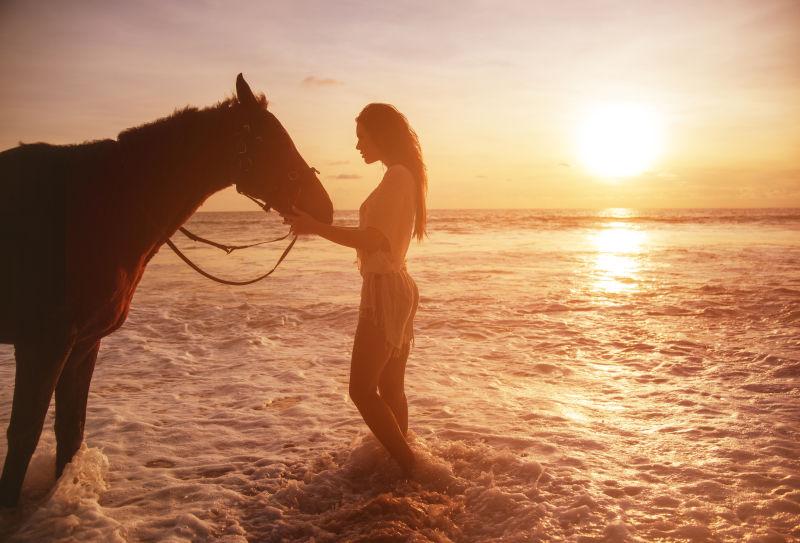 漂亮女人在海水里抚摸心爱的马