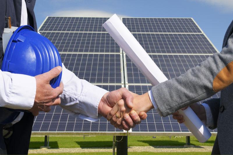 太阳能电池板前握手的两个人