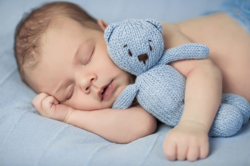 熟睡的婴儿抱着蓝色的小熊