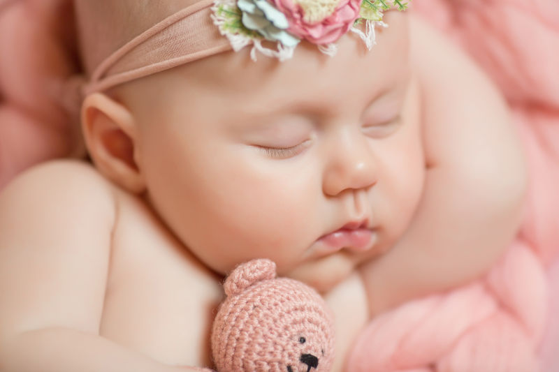 可爱的婴儿抱着粉色的布偶睡觉