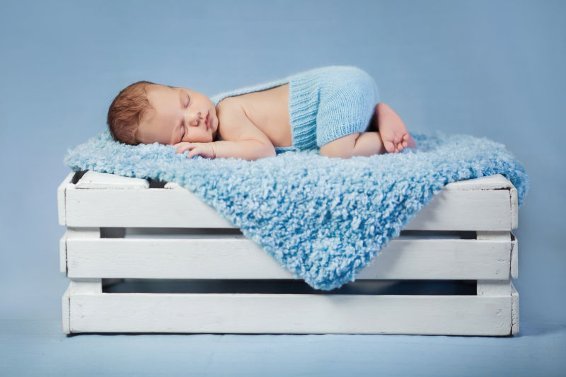 可爱的婴儿躺在蓝色的毯子上