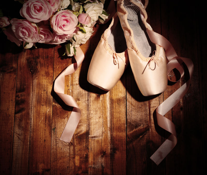 木桌子上的芭蕾舞鞋和花束