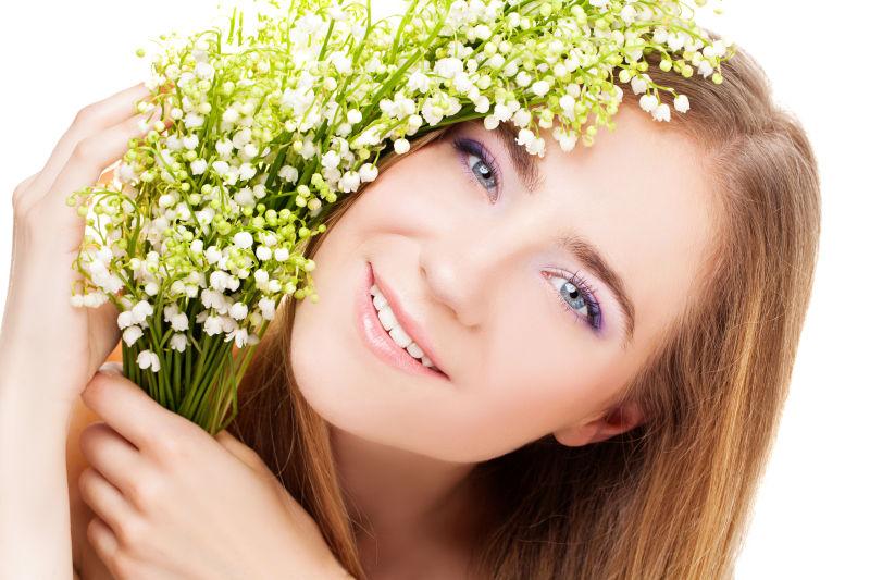 年轻美丽的微笑金发女人抱着山谷百合花