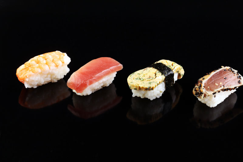 黑色背景中的四个口味的寿司
