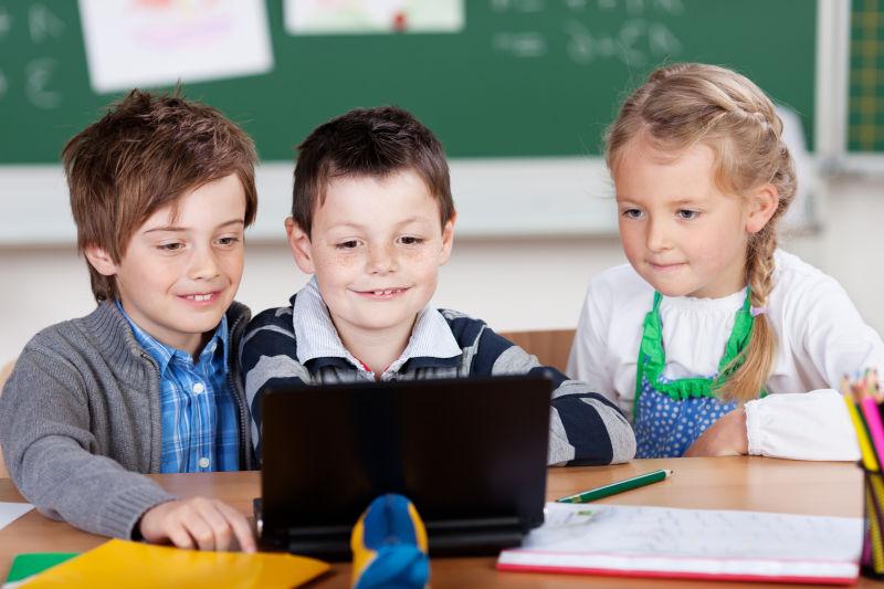 在教室内使用笔记本电脑的三个学生