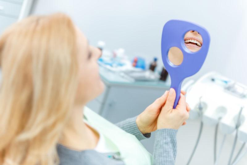 牙诊所对着镜子看牙的女人