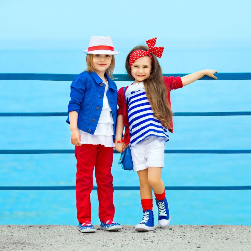 站在海边的两个时尚的小女孩