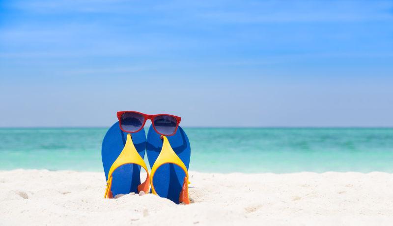 沙滩上的旅游拖鞋和太阳镜