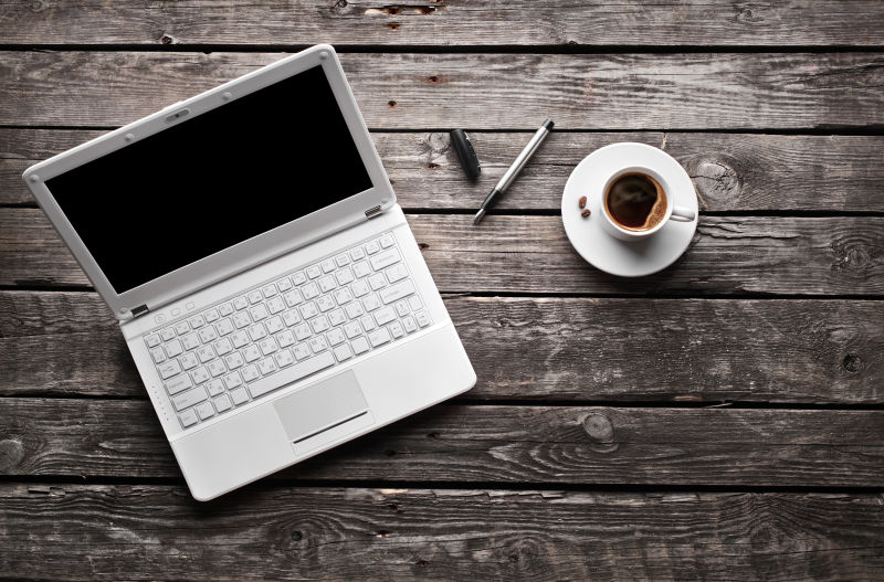 木桌上的白色笔记本电脑和一杯咖啡