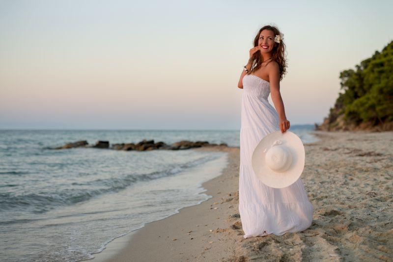 海滩上穿着白色裙子的微笑中女人