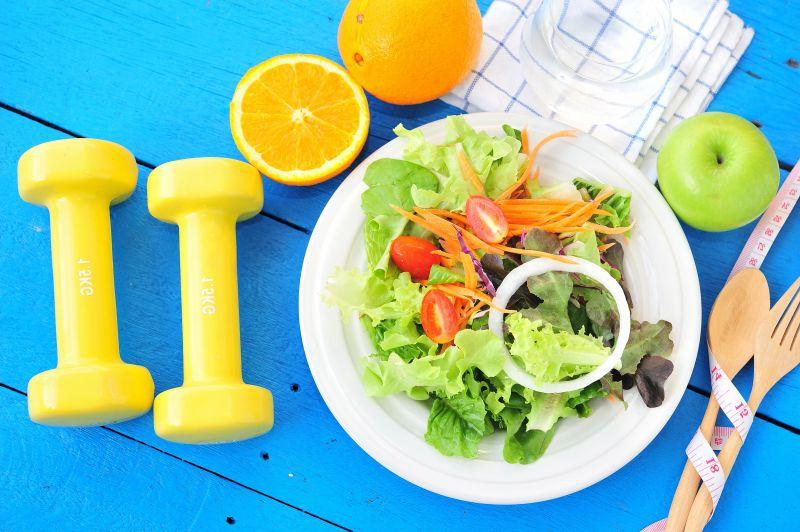 桌子上的哑铃和水果蔬菜沙拉