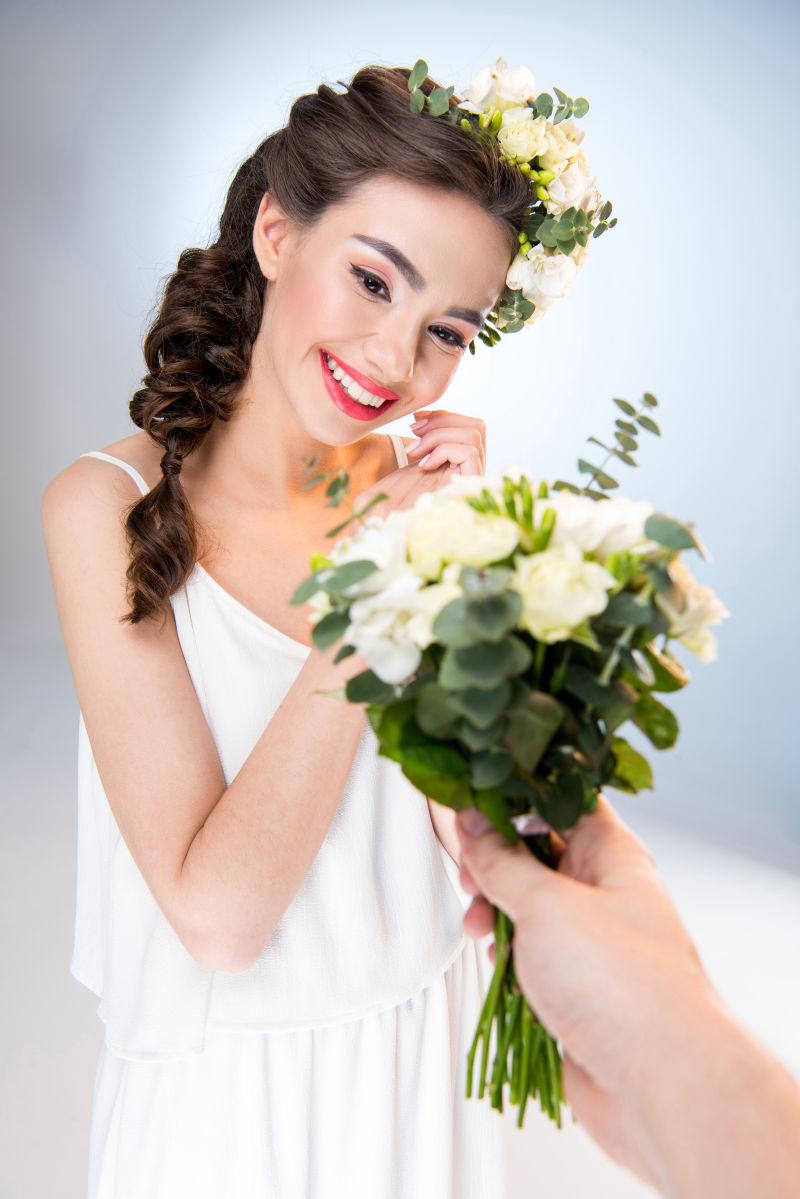 微笑的女人在白色的花束上接受鲜花