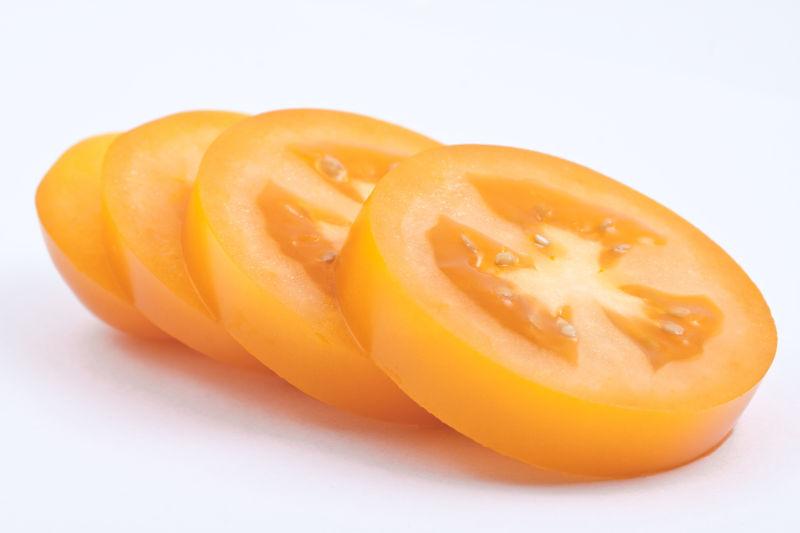 白色背景下的切成圆形的黄色番茄