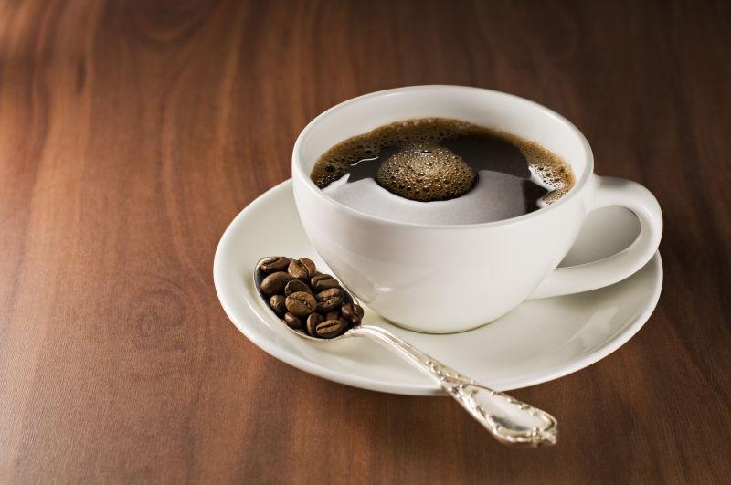 一杯精致的热咖啡和勺子的咖啡豆