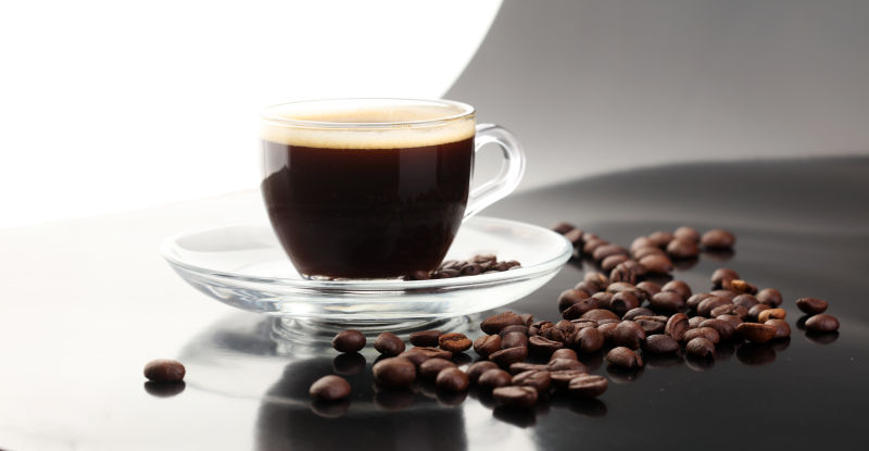 黑色平台上的黑咖啡与咖啡豆