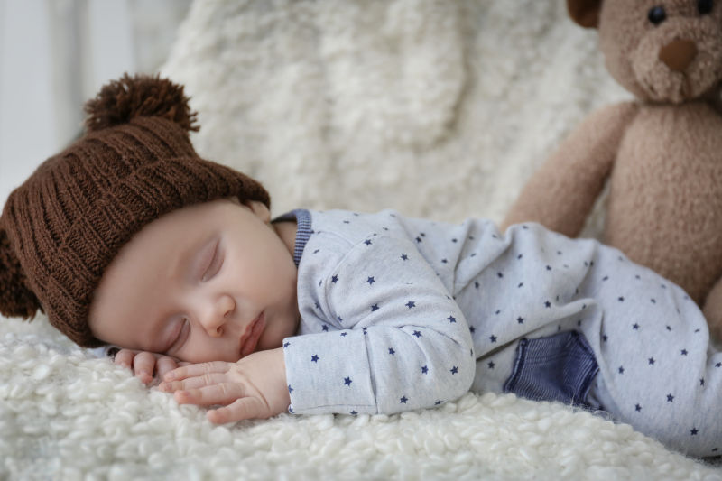 戴着帽子睡在地毯上的婴儿