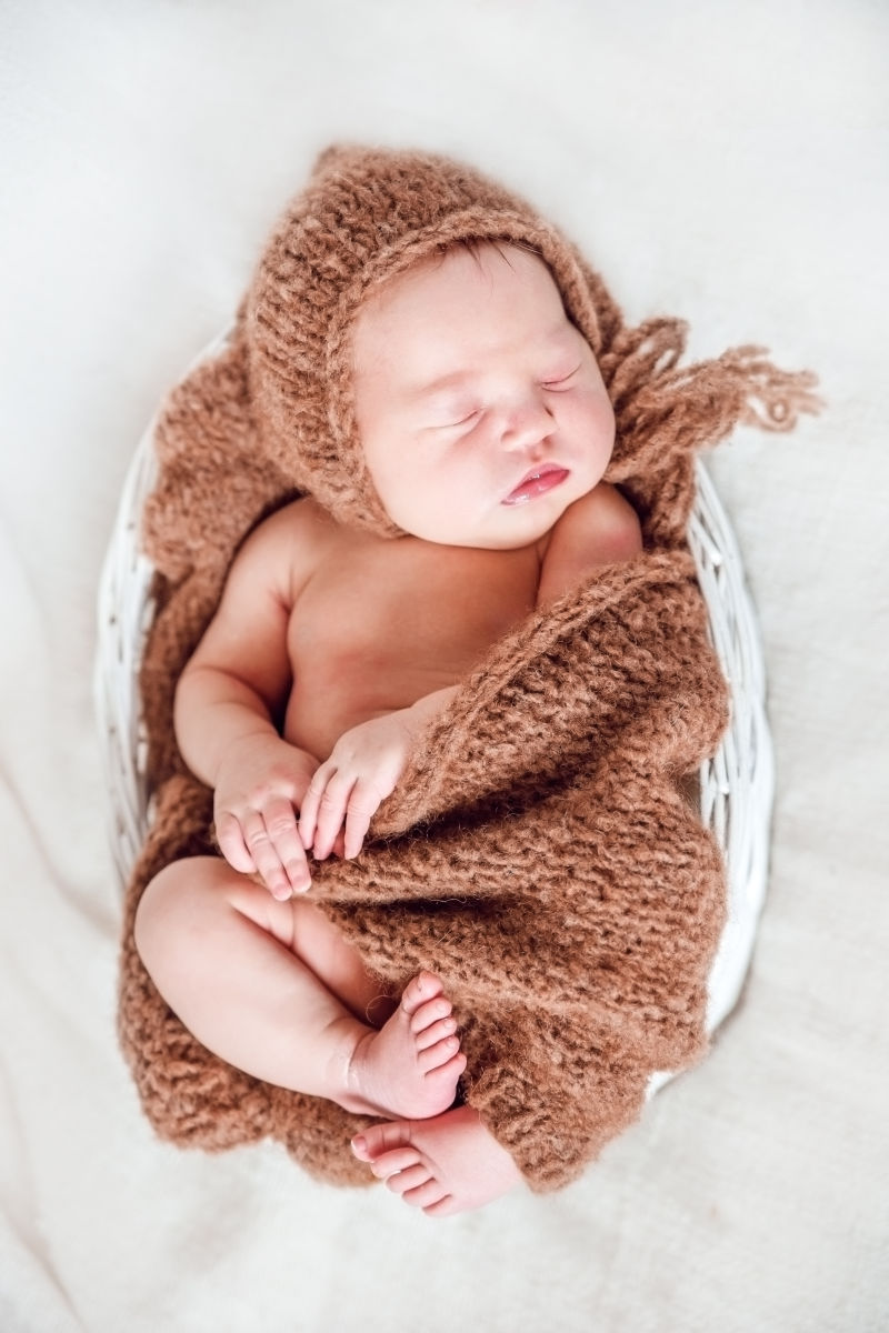 裹着编织睡衣在篮子里睡觉的婴儿