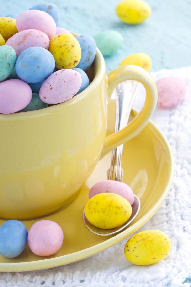 白色背景上黄色咖啡杯里的复活节彩蛋