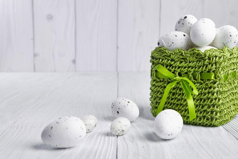 白色桌上和绿色篮子里黑白相间的复活节彩蛋