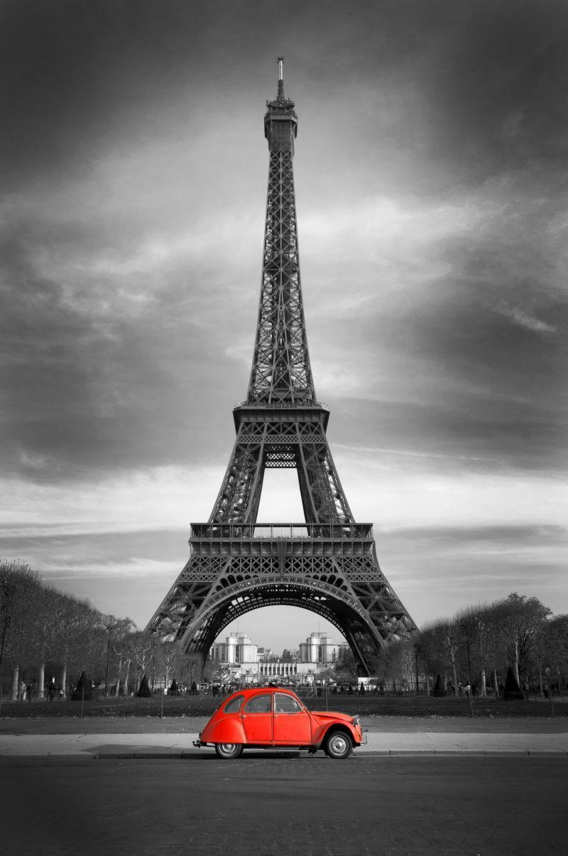 巴黎埃菲尔铁塔前边行驶着一辆红色轿车