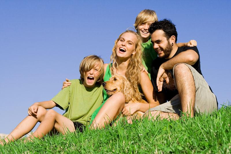 蓝天下坐在草地上微笑的一家人