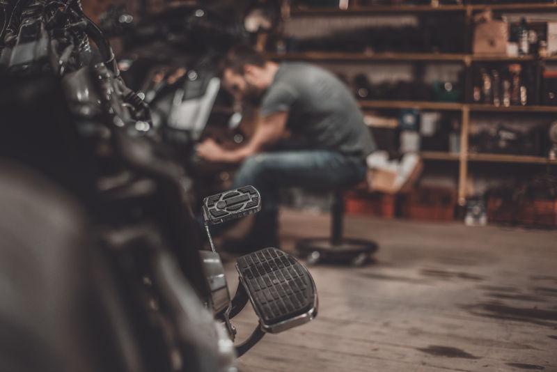 汽车修理厂维修摩托车的男人
