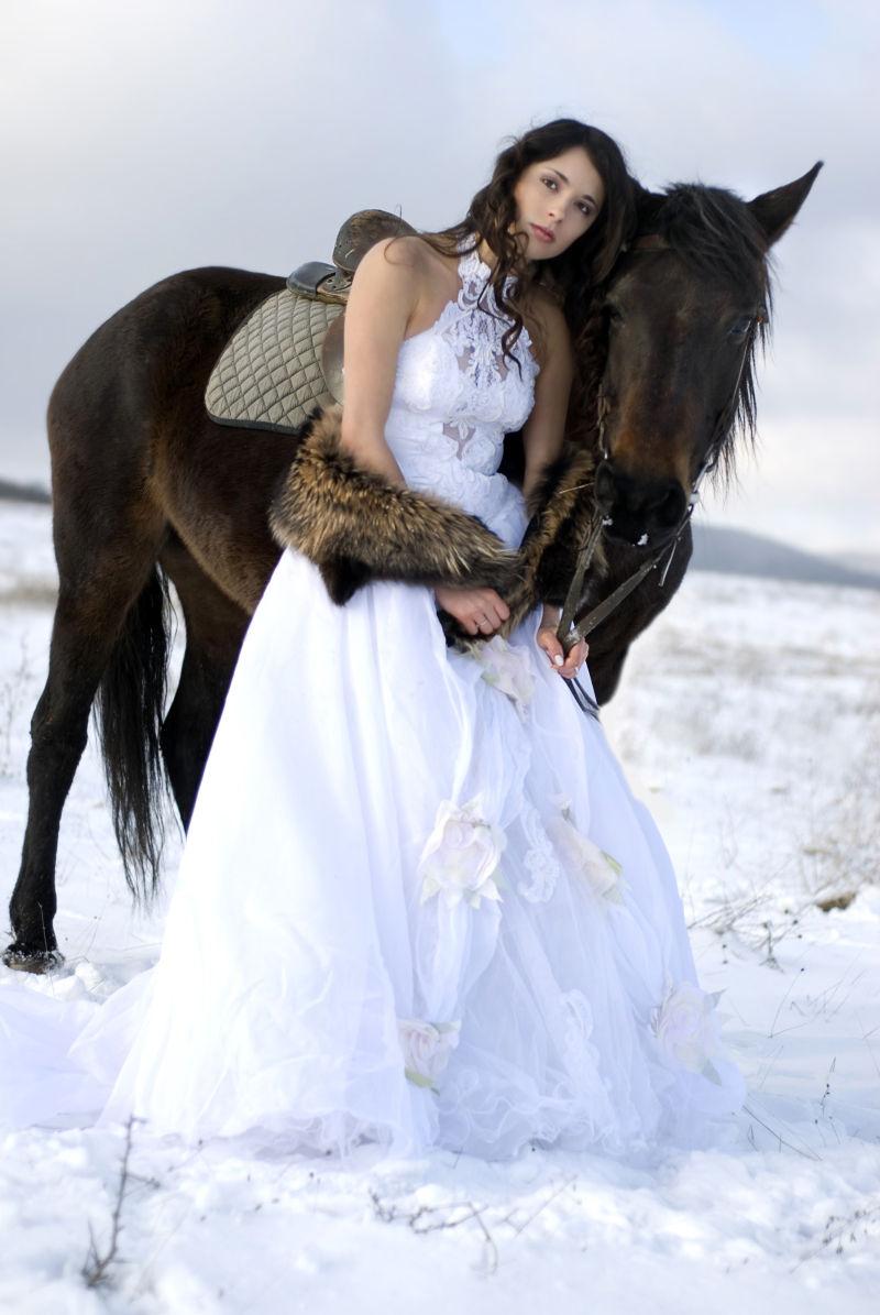 雪地里穿婚纱的女子和一匹马