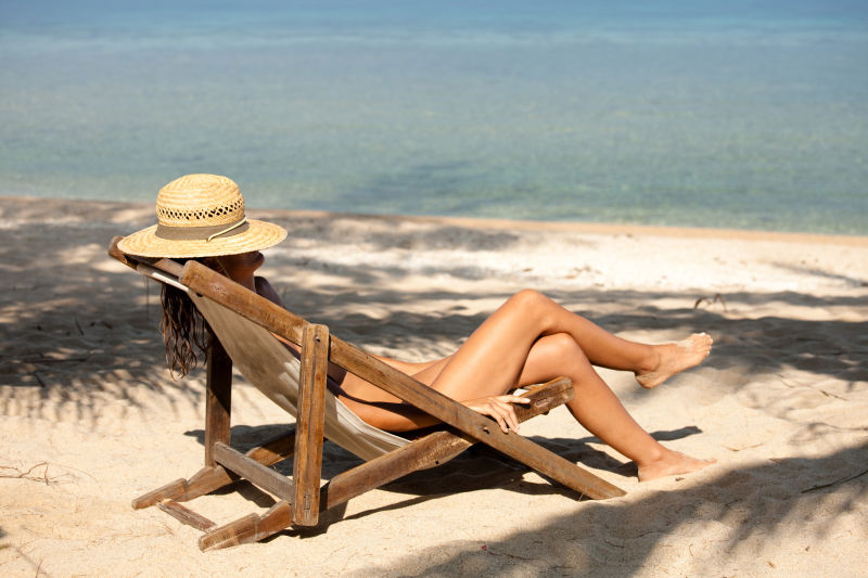 坐在沙滩椅上的美女带着草帽
