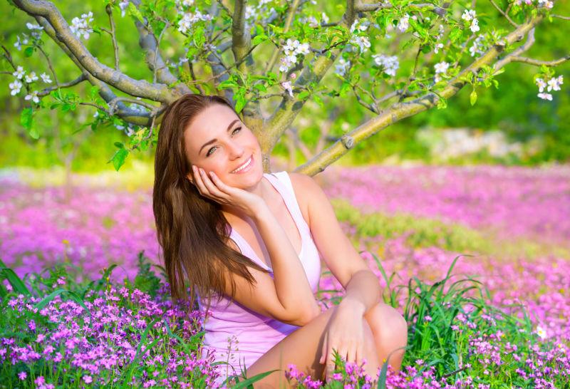 坐在粉色花丛中的可爱的女人