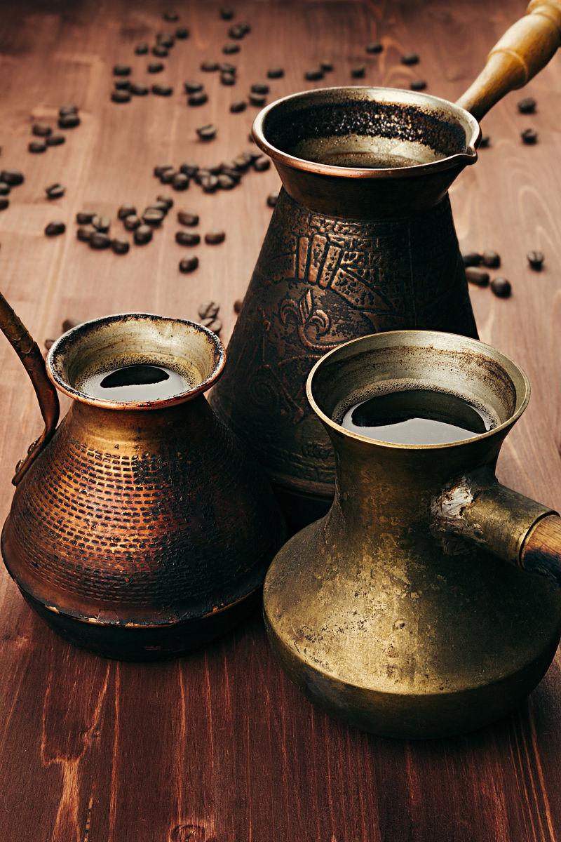 棕色木桌上的土耳其铜锅咖啡和咖啡豆