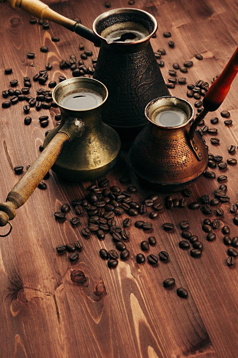 土耳其铜锅里的咖啡和棕色木桌上的咖啡豆