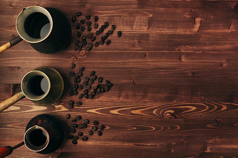 棕色木桌上的咖啡豆和铜锅里的咖啡