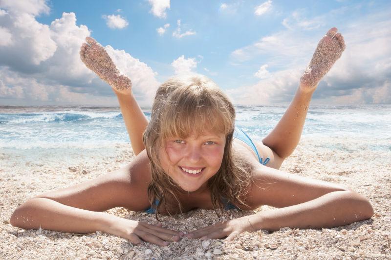 趴在沙滩上微笑的小女孩