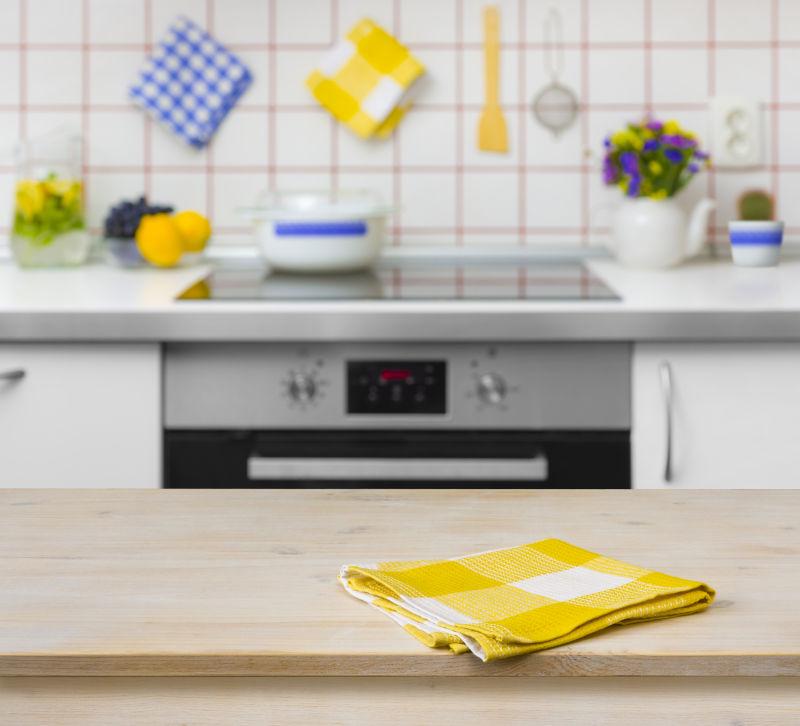 厨房背景的黄色餐巾木桌