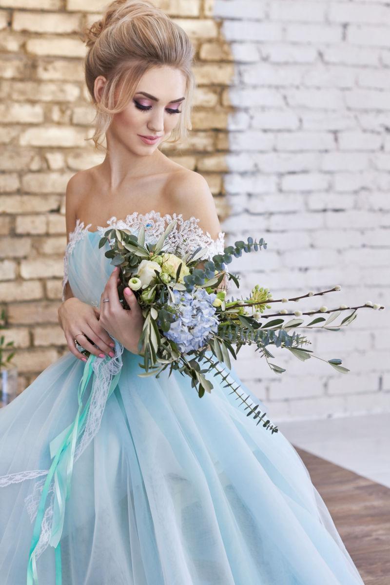 穿着蓝色婚纱的新娘捧着一束美丽的花束