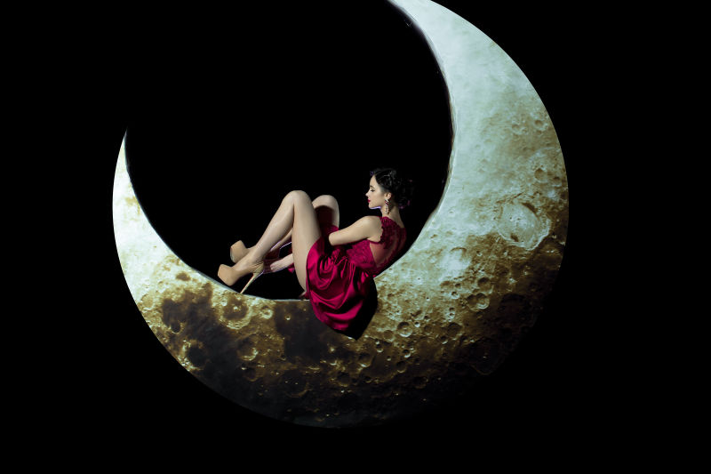 黑色背景上躺在月亮上的美女