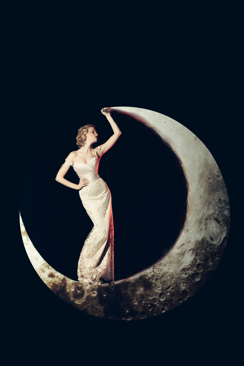 黑色背景上站在月亮上的美女
