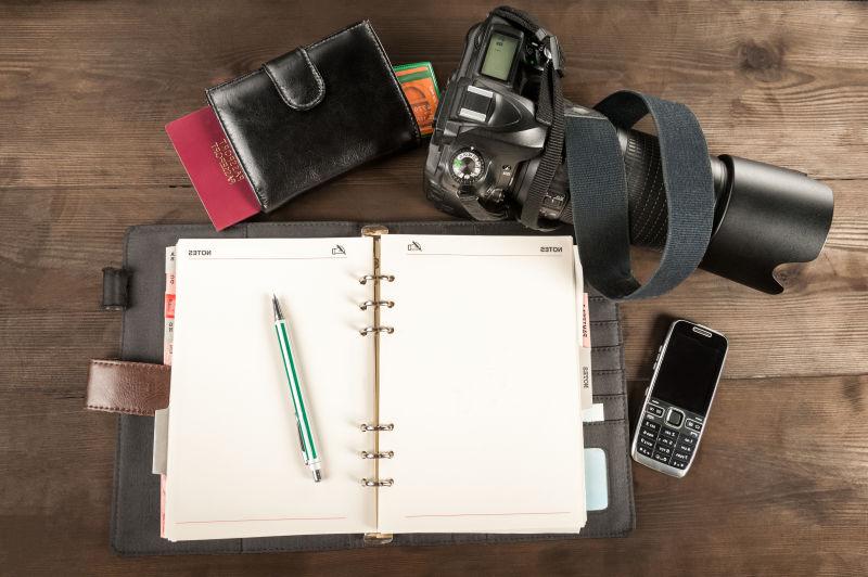 木桌上准备旅行用的照相机和老式记事本