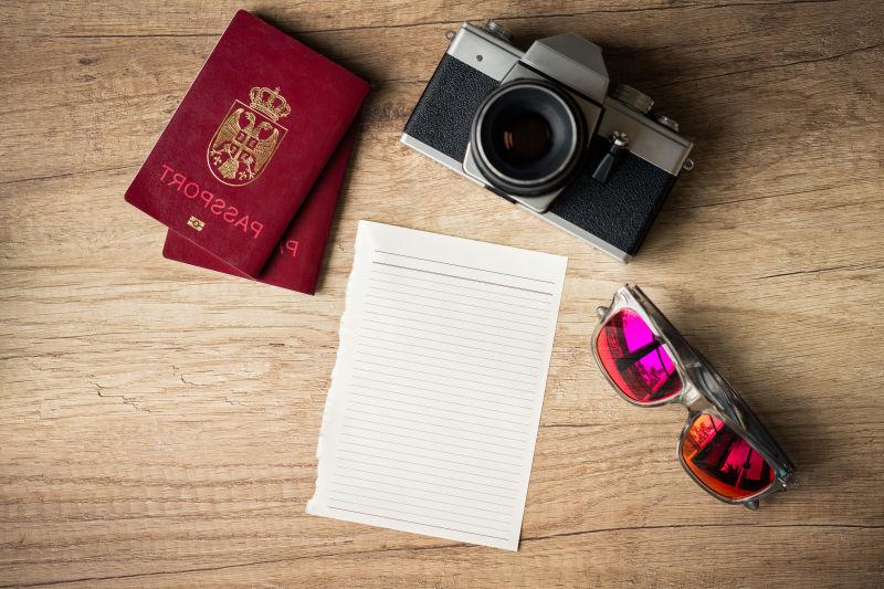 木桌上的护照照相机和太阳镜等旅行用品